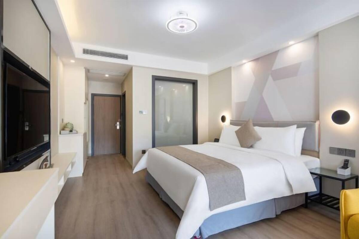 Ein modernes Hotelzimmer mit einem großen Bett, Nachttischen, einem Flachbildfernseher und einem begehbaren Kleiderschrank.