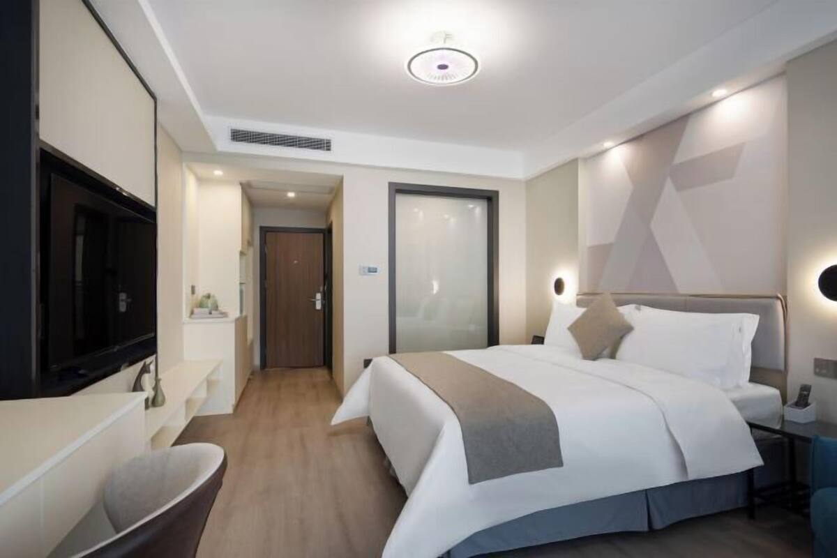 Ein modernes Hotelzimmer mit Bett, Nachttisch, Fernseher und einem Badezimmer mit Badewanne.