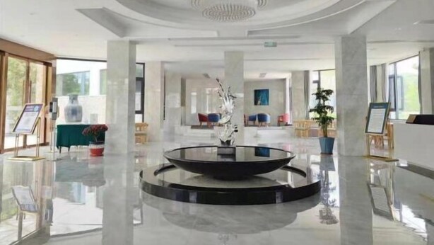 Eine großzügige Lobby mit einer zentralen, runden Wasserspüle, großen Fenstern und einer modernen Deckenleuchte.
