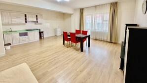 A modern apartment with a kitchen, dining area, and a large window with curtains. - Negdelchin Hotel & Service Apartment (Ulaanbaatar)