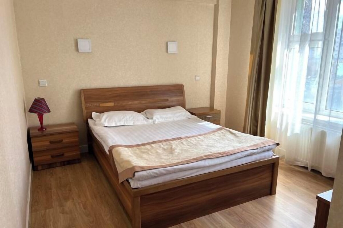A neatly made bed with a wooden headboard, a bedside lamp, and a nightstand.