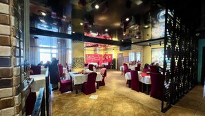 A restaurant with red chairs and white tablecloths, featuring a tiled floor and brick walls. - Negdelchin Hotel & Service Apartment (Ulaanbaatar)