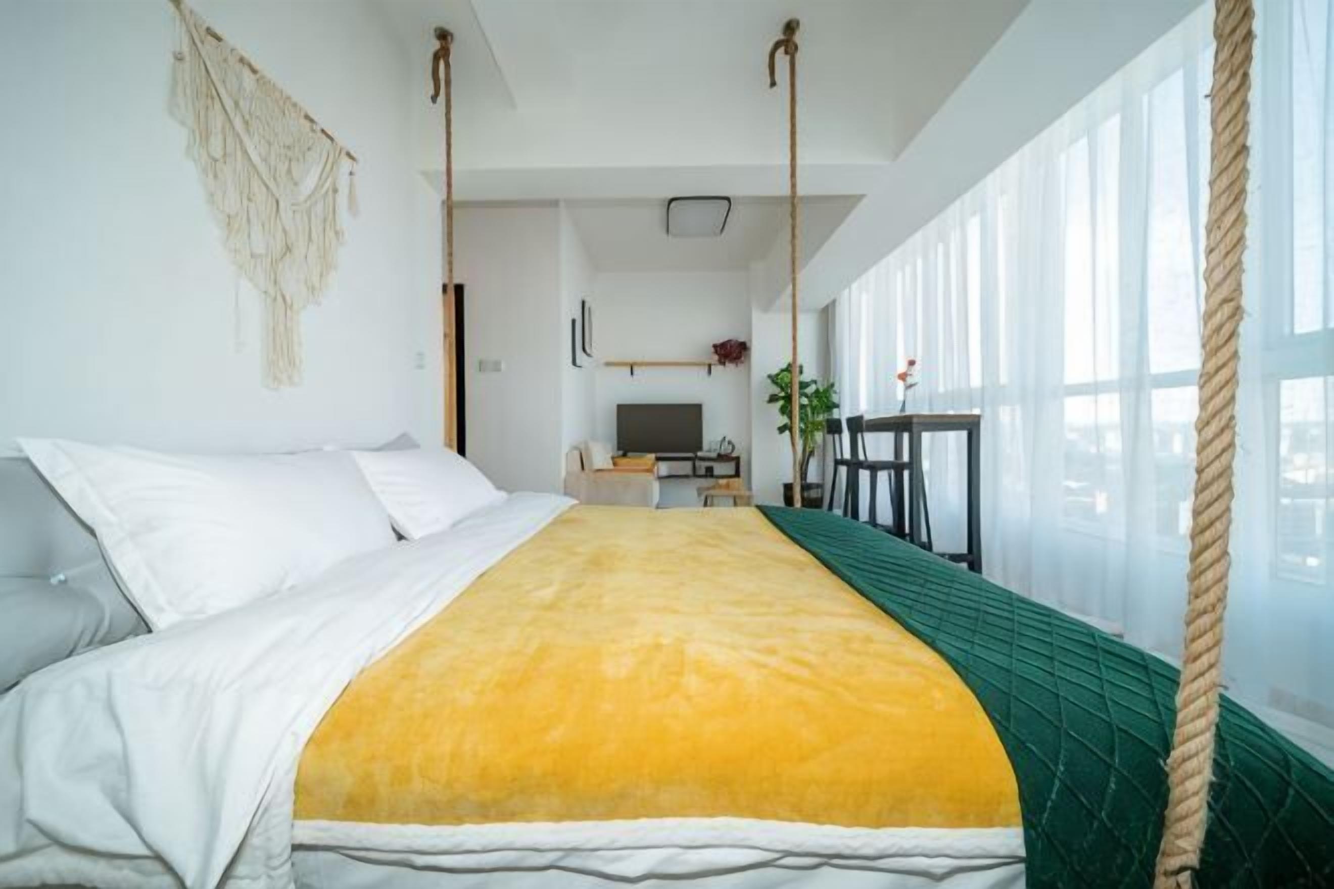 A room with a bed, a desk, a television, and a large window.