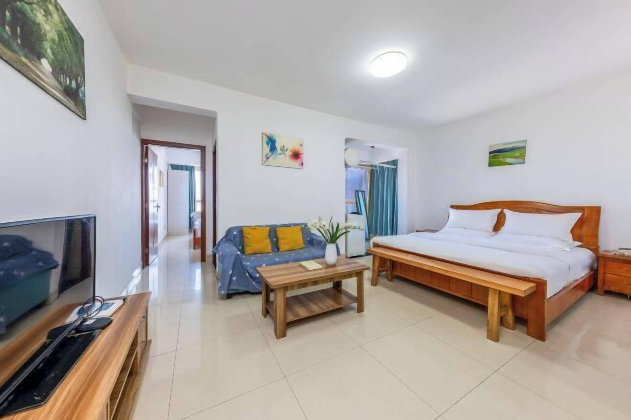 A hotel room with a bed, a sofa, a coffee table, a TV, and a desk.