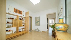 Una habitación con estanterías de madera, un jarrón grande y un cuadro en la pared.