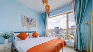 A bedroom with a bed, a nightstand, a window with curtains, and a city view. - Caiyun Jiayuan (Nanping Street Old Street Kunming) (Kunming)