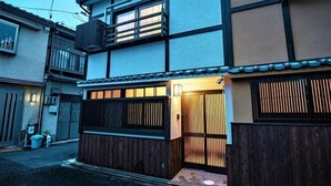 Un edificio in stile tradizionale giapponese, con cancello in legno, un piccolo portico e una porta scorrevole.