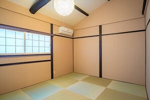 A tatami mat room with a sliding door, a ceiling fan, and a window with a grid pattern. - Kyoran Suigetsutei (Kyoto)