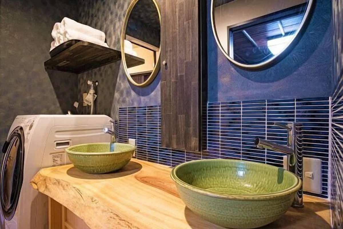 Een badkamer met een grote, groene wastafel, een wasmachine, een spiegel en een handdoekhouder.