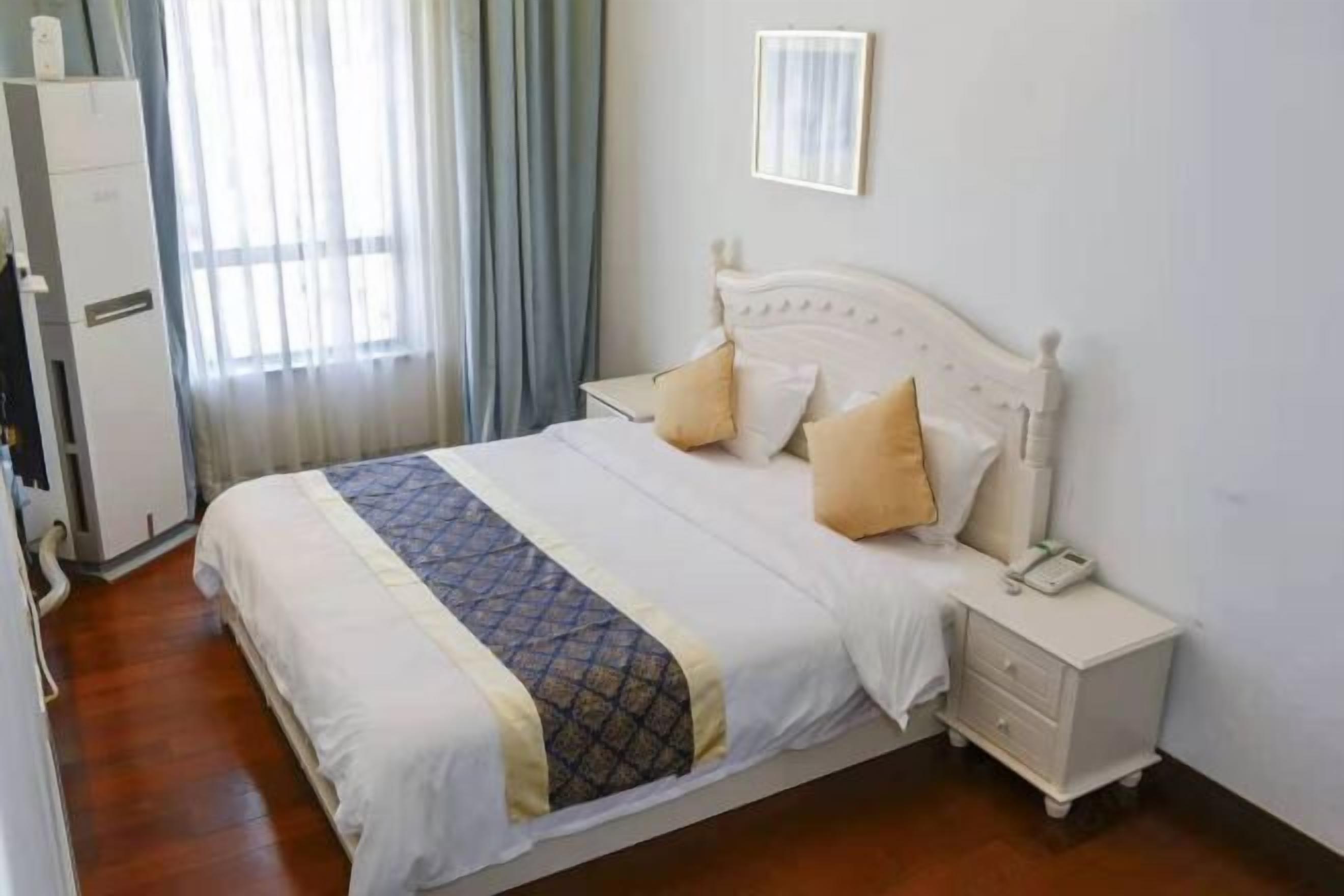Une chambre d’hôtel avec un lit, une table de chevet avec un téléphone et une armoire.