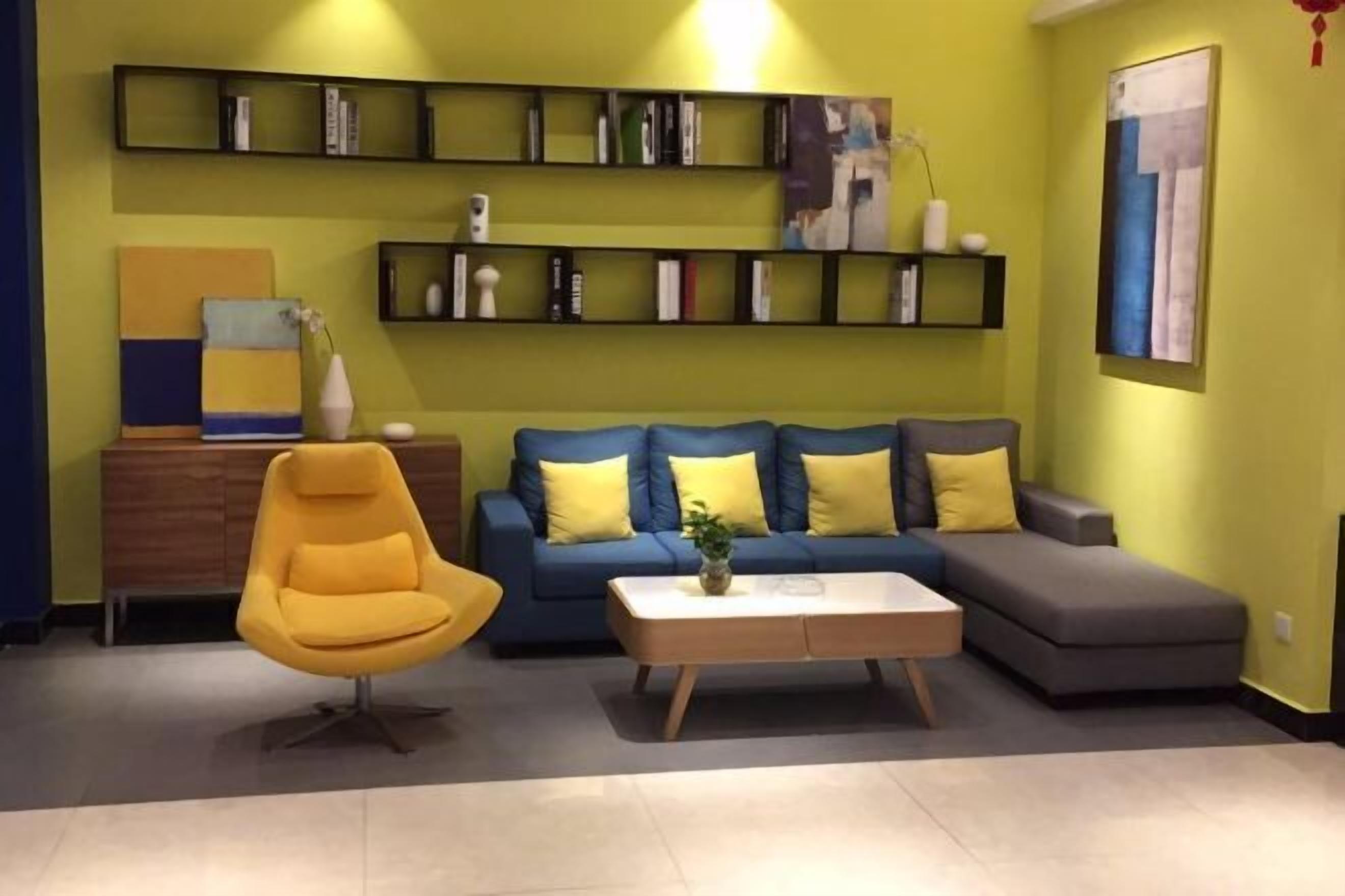 A living room with a yellow sofa, a yellow armchair, a coffee table, and a bookshelf.