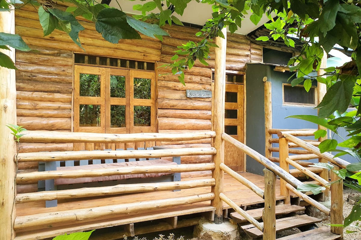 A rustic wooden cabin with a wooden porch and a staircase leading to the entrance.