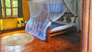 Una cama de madera con dosel, un tapete tejido y una ventana con cortinas.