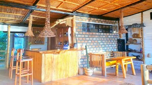 Un área de bar rústica con pared de ladrillo, muebles de madera y lámparas colgantes.