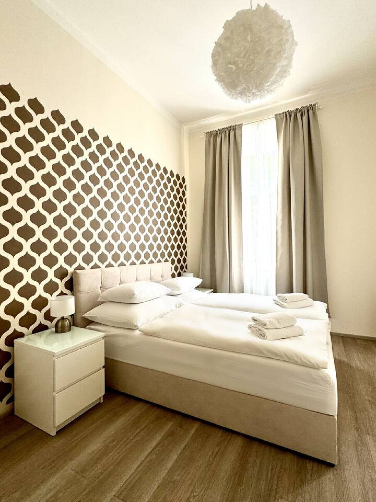 Camera da letto con un letto, un comodino e un motivo decorativo al muro.