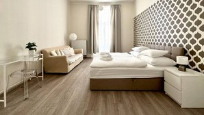 Een moderne hotelkamer met een bed, bureau, bank en een behang met patroon.