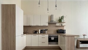 Een moderne keuken met witte kasten, een inbouwoven en een magnetron.