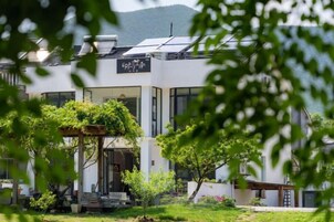 Un edificio moderno con vestíbulo cubierto, paneles solares y un jardín.