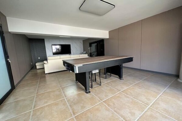 Una cocina moderna con mesa de billar integrada, un sofá y televisor de pantalla plana.