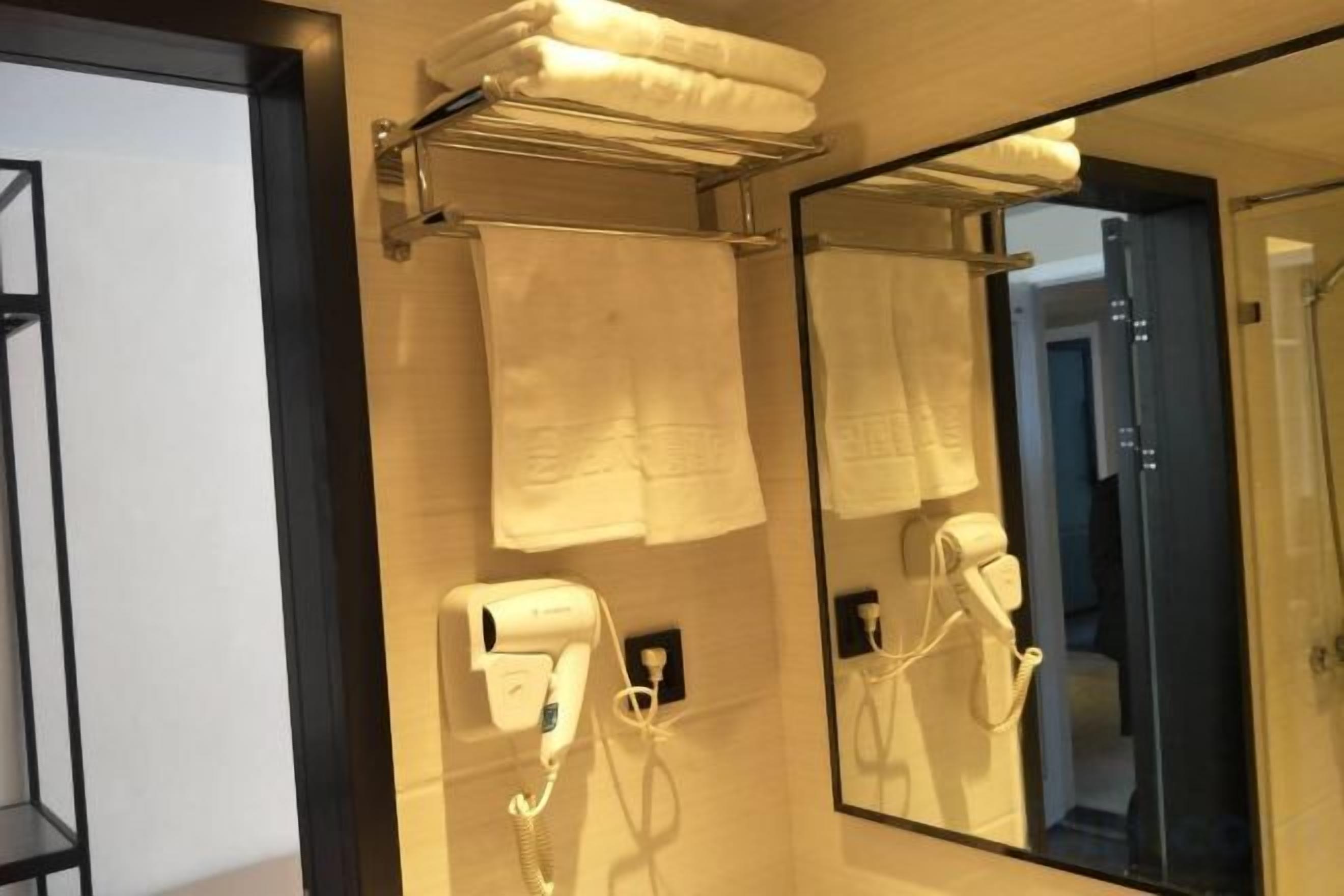 A bathroom with a towel rack, a hairdryer, and a mirror.