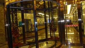A revolving door with glass panels, marble flooring, and a red carpet. - Huilong Dasha Hotel (Chengde)