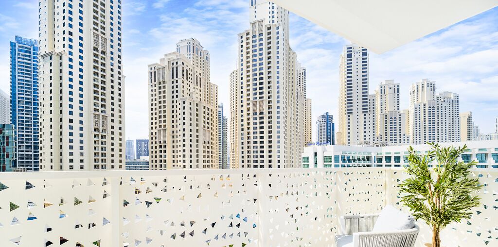 Ein hoch aufragendes Gebäude mit modernem Design, das eine Reihe von Balkonen und einen Blick auf andere hohe Gebäude im Hintergrund bietet.