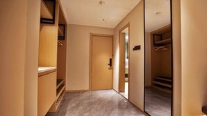 A hallway with a wooden wardrobe, a mirror, and a door leading to another room. - Songguo Hotel (Zhengzhou Tongbai Road Central Hospital Metro Station) (Zhengzhou)