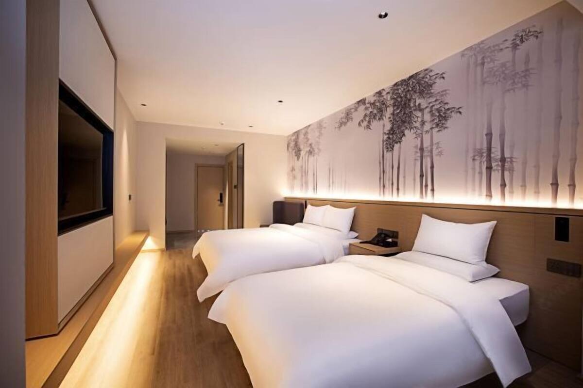 Habitación de hotel con dos camas, un mural grande en la pared, televisión y suelo de madera.