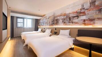 A hotel room with three beds, a round table, and a large abstract painting on the wall.