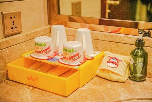 A bathroom with a yellow soap dish, two white cups with cartoon designs, a towel with a cartoon character, and a bottle of lotion. - Qian dao Lake Hotel Hangzhou (Chun'an)