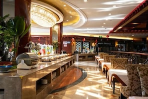 Un vestíbulo de hotel con bufé, zona de estar y bar.