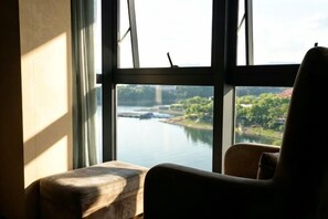 A room with a large window overlooking a river and greenery.