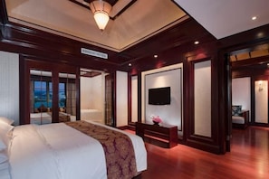 A hotel room with a large bed, a television, a desk, and a view of the outdoors.