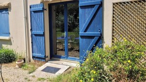 A building with blue shutters, a patio with a table and chairs, and a small garden area. - Maison Sarzeau / Saint Gildas de Rhuys (Sarzeau)