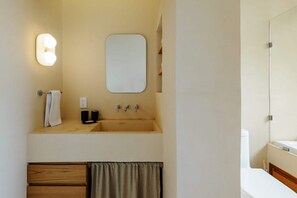 Un baño con lavamanos, espejo, toallero y retrete.