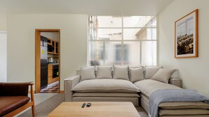 A modern living room with a sofa, a coffee table, and a view of the kitchen through a glass door. - w* | Captivating 2BR with Balcony  in Roma Norte (Ciudad de México)