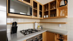 A modern kitchen with wooden cabinets, a stainless steel refrigerator, a built-in microwave, a gas stove, and a coffee maker. - w* | Captivating 2BR with Balcony  in Roma Norte (Ciudad de México)