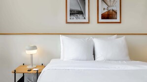 A hotel room with a neatly made bed, a bedside table with a lamp, and two framed photographs on the wall. - w* | Captivating 2BR with Balcony  in Roma Norte (Ciudad de México)