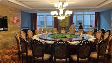A formal dining room with a round table, ornate chairs, and a chandelier.