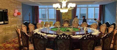 A formal dining room with a round table, ornate chairs, and a chandelier.
