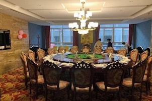 A formal dining room with a round table, ornate chairs, and a chandelier.