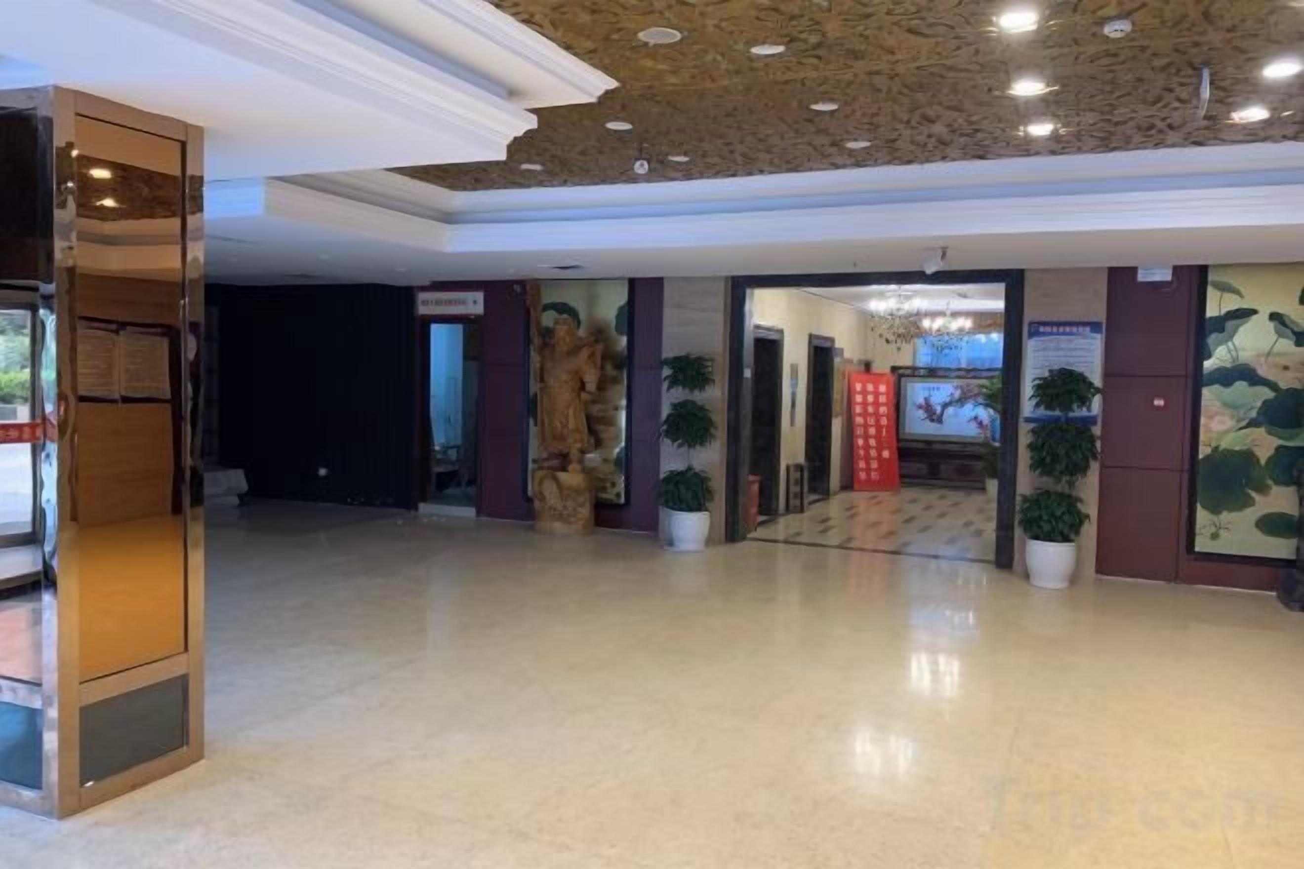 Un vestíbulo amplio con piso pulido, una estatua y plantas en macetas.