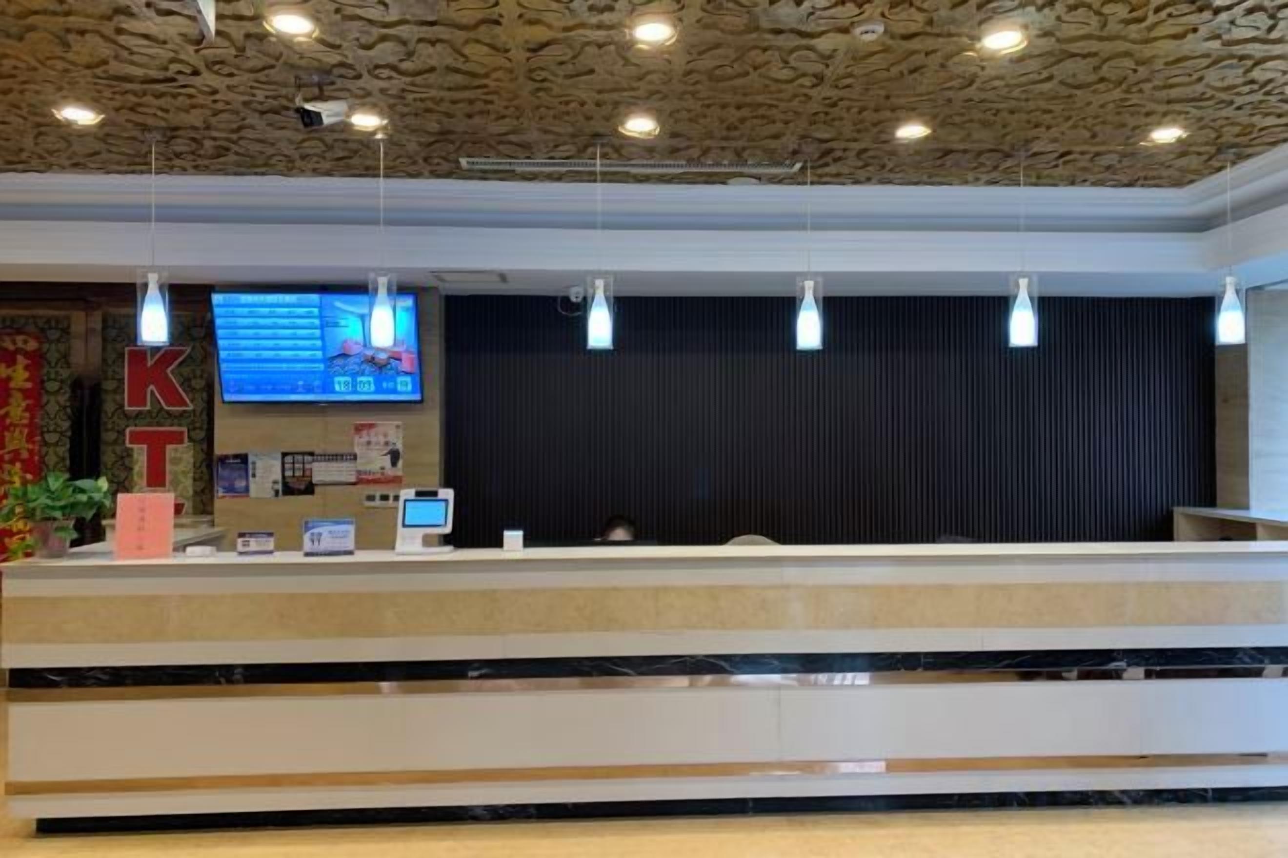 A hotel reception area with a stone ceiling, a reception desk, and a digital screen displaying information.