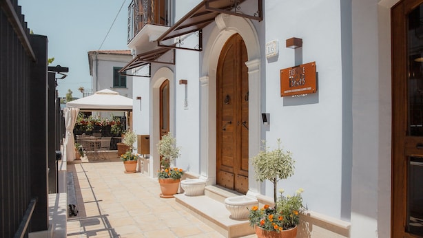 Una calle estrecha con edificios blancos, puertas de madera y plantas en macetas.