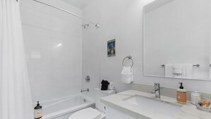 A modern bathroom with a bathtub, toilet, and sink. - Vermithor's Bronze Ember Sweet Suite (Seattle)