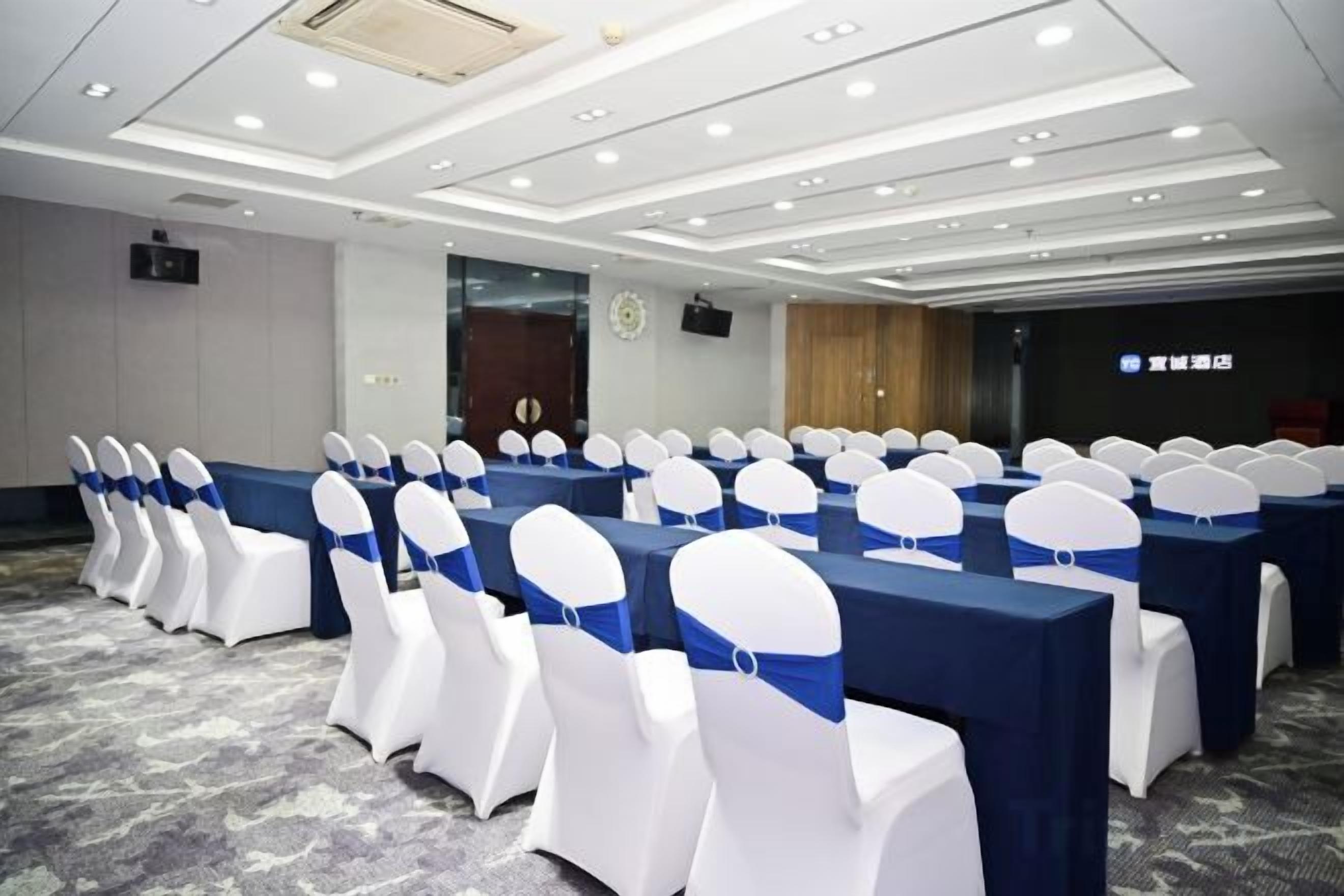 A conference room with rows of tables and chairs, a carpeted floor, and a clock on the wall.