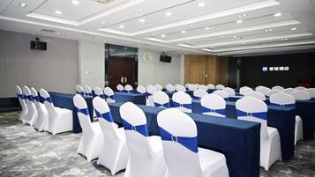 A conference room with rows of tables and chairs, a carpeted floor, and a clock on the wall.