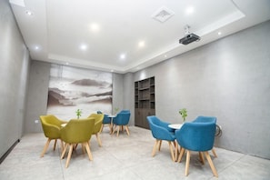 A modern meeting room with a large mural, blue and yellow chairs, and a projector on the ceiling.
