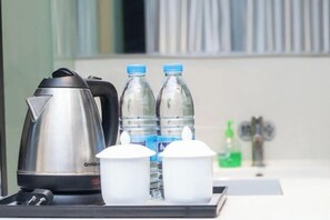 Uma kitchenette com chaleira, duas garrafas de água e dois recipientes brancos sobre um tabuleiro.