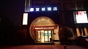 Ein Hotel Eingang mit einem Schild, das "宜诚酒店" zeigt, und einer großen, beleuchteten Werbung auf der rechten Seite.